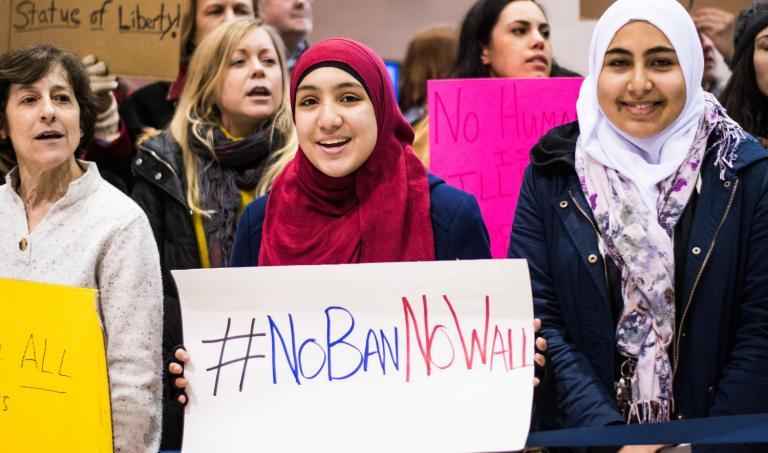 woman wearing hijab holds sign that says "No Ban, No Wall"